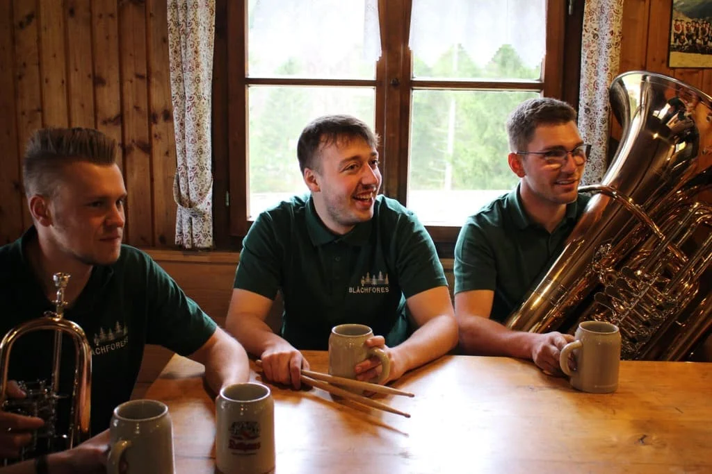 Musiker sitzen mit Instrumenten an einem Holztisch