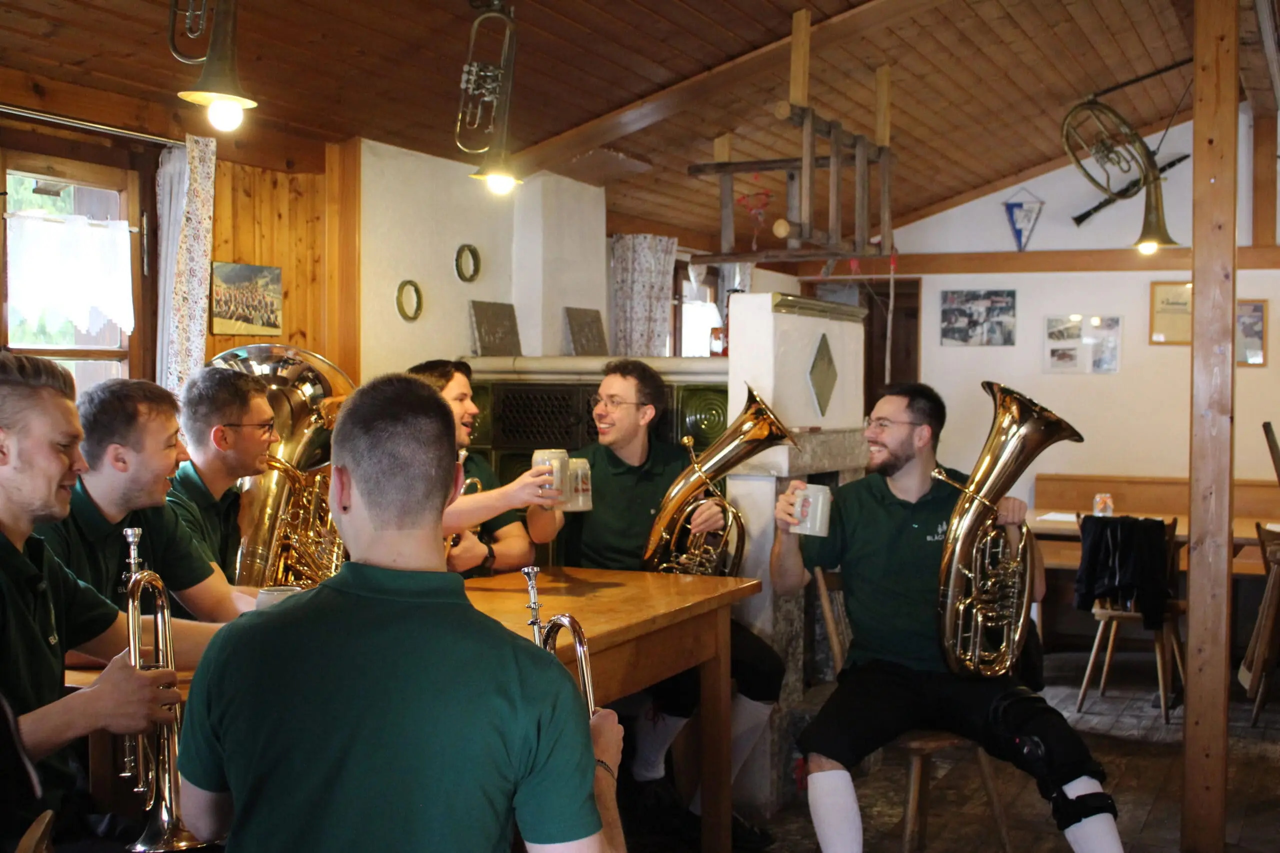 Sieben Männer sitzen gesellig mit ihren Instrumenten am Tisch.